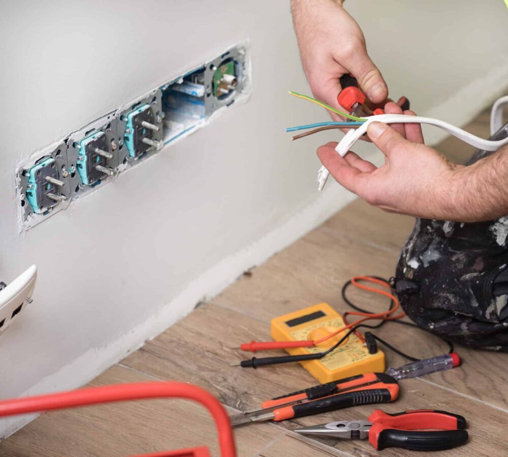 An electrician is installing a wall socket for a domestic client.