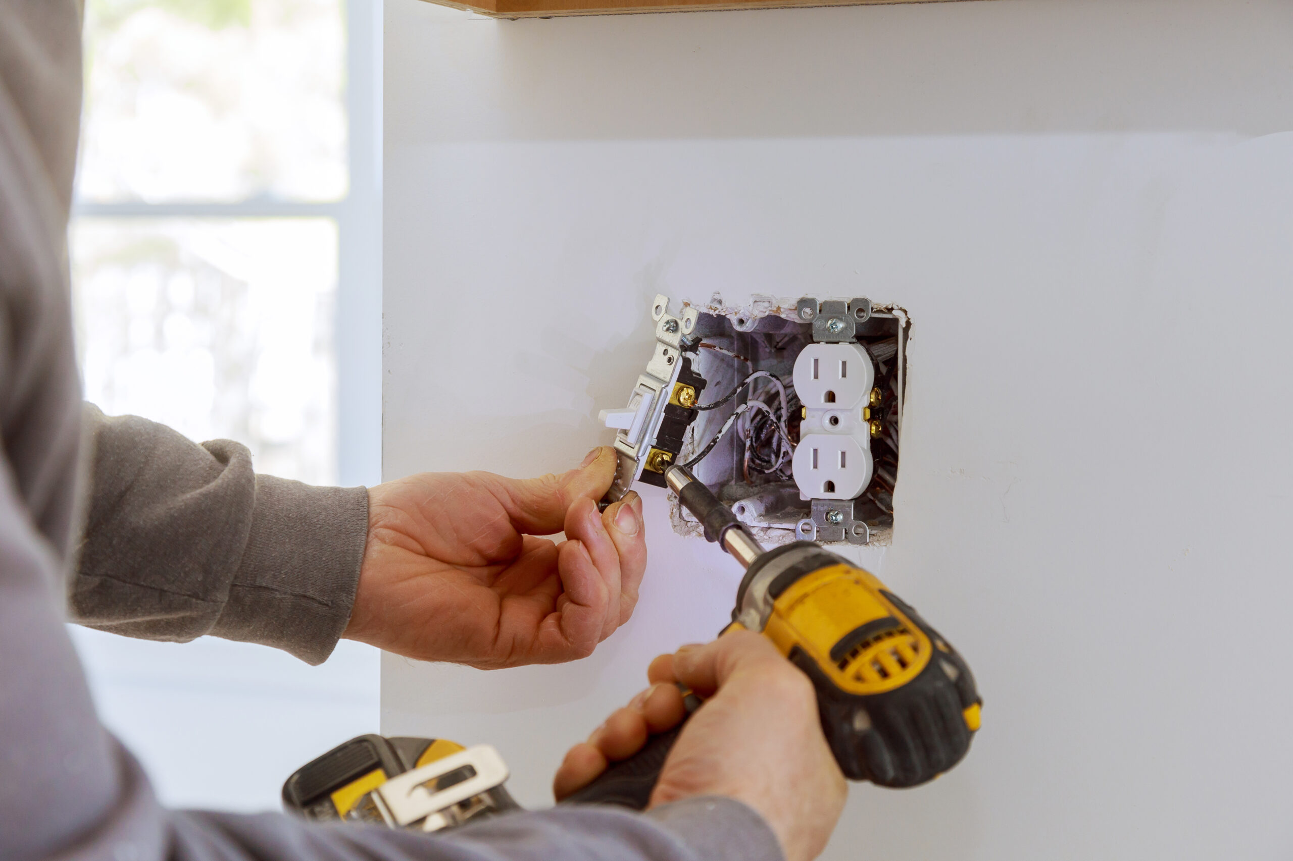 An electrician installing a wall socket as part of reliable domestic electrical services, providing a safe and professional home wiring solution
