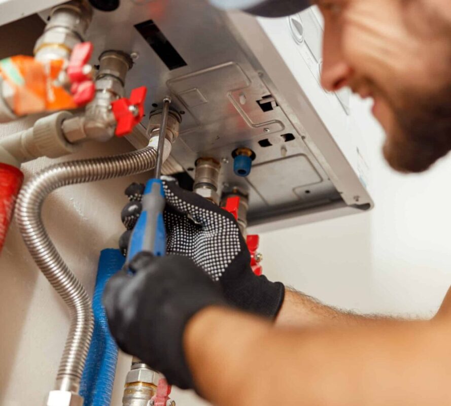 A heating technician performing repairs and maintenance on a gas boiler.