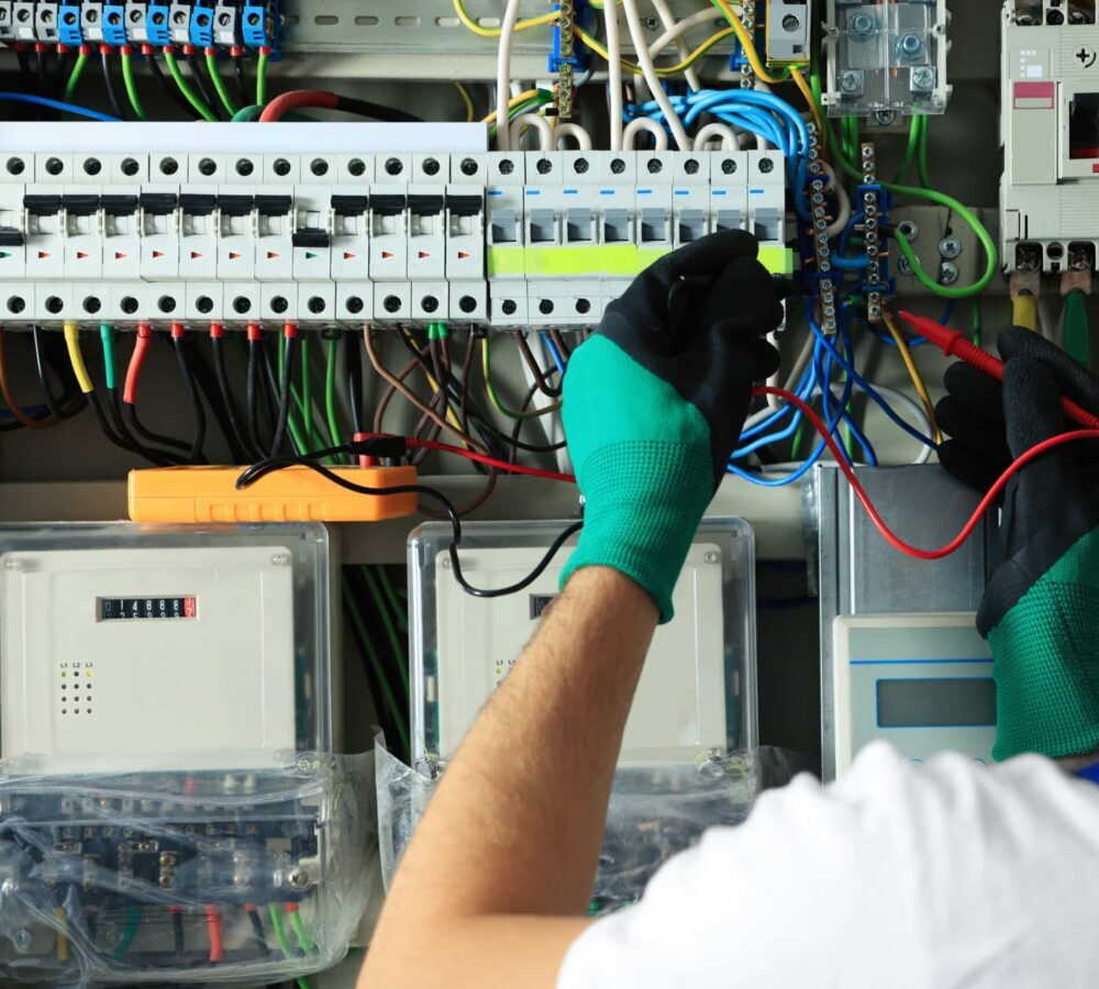 Electrician checking electric current with multimeter indoors, closeup