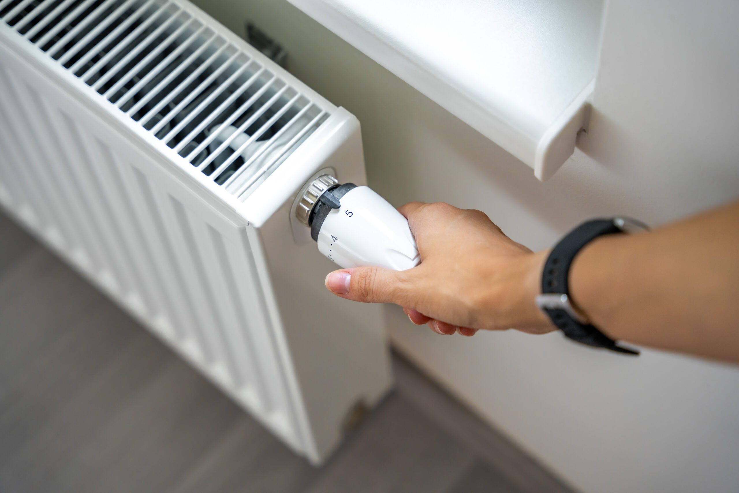 A heating technician adjusting a heating knob on a radiator