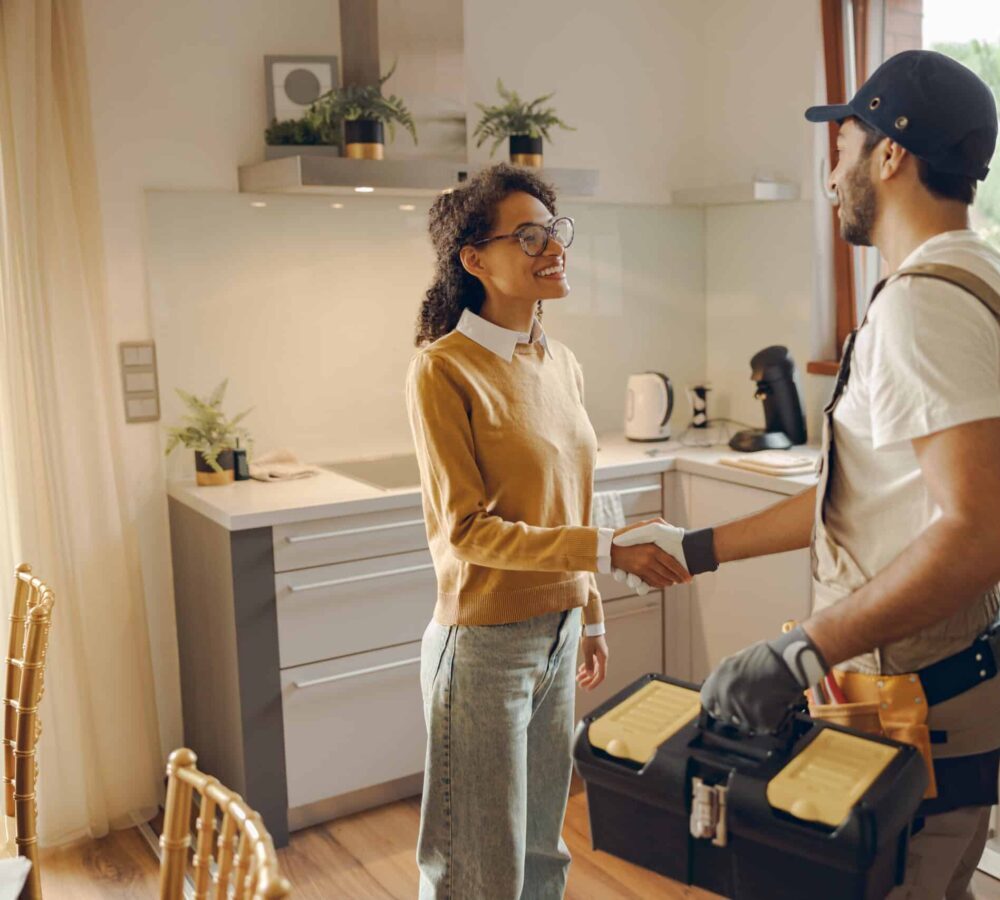A heating engineer shakes hands with a satisfied client after completing boiler repair and maintenance.