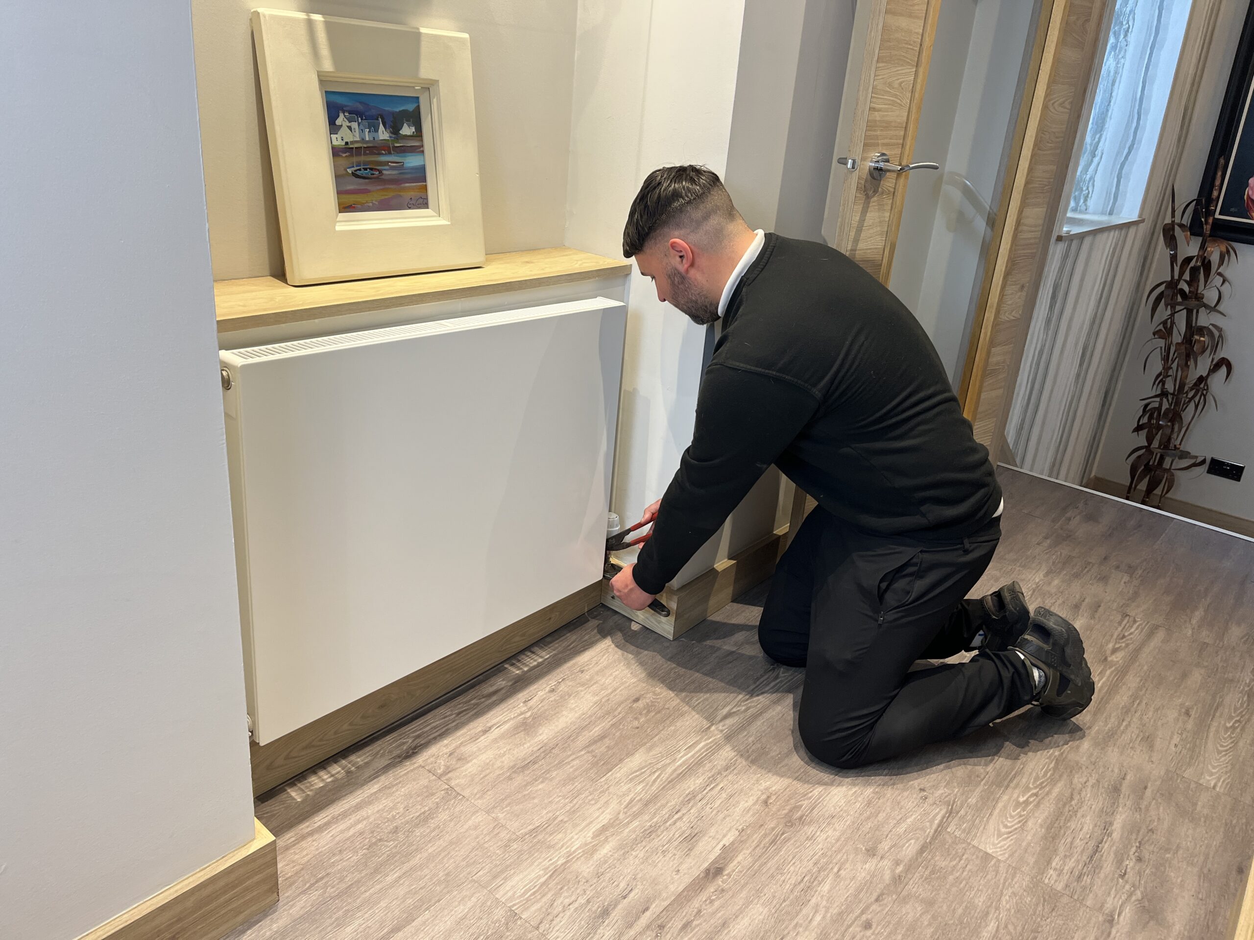 An expert heating technician servicing a radiator for a homeowner after a central heating system installation.