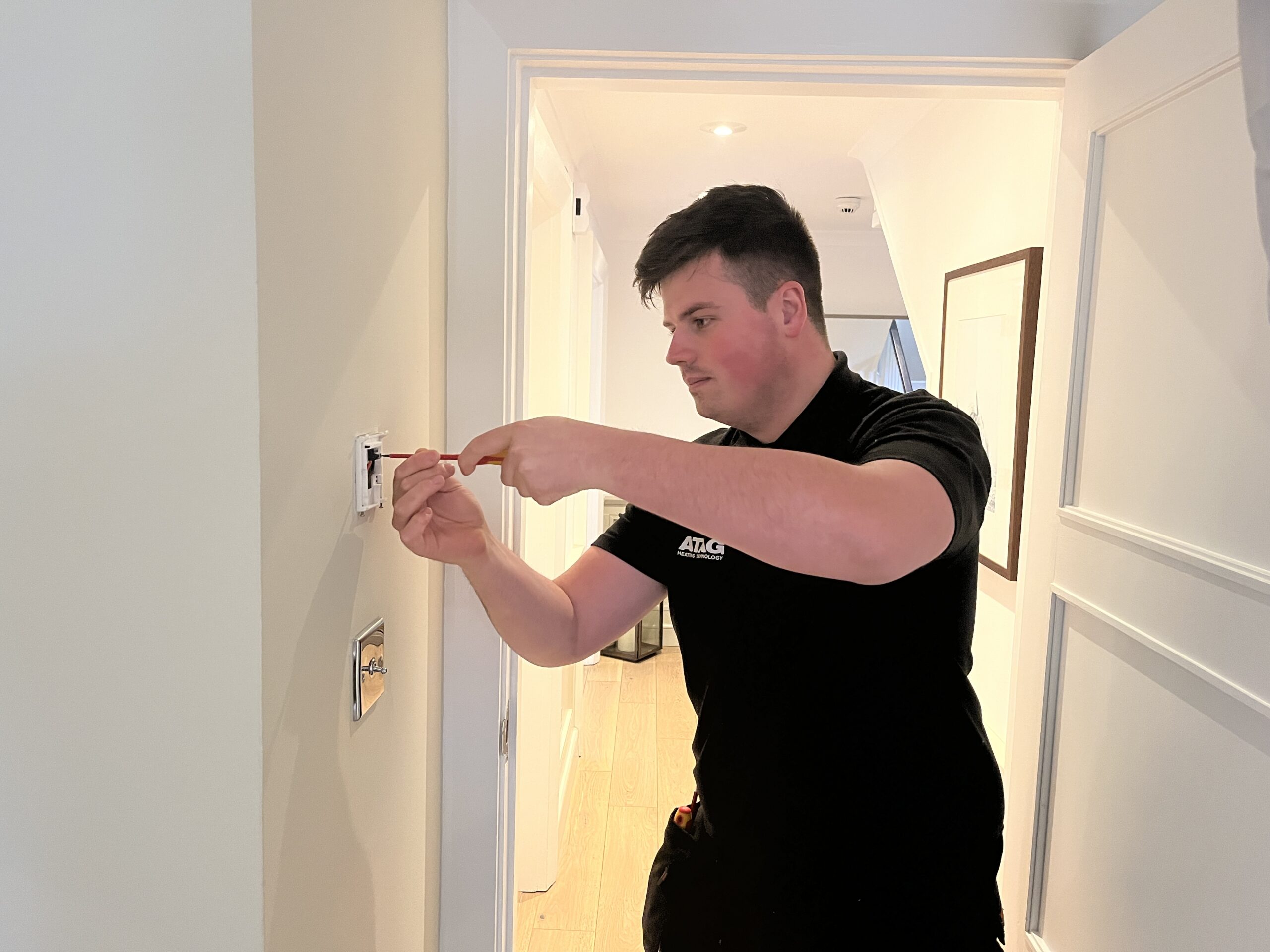 An electrician from L.W. Haddow Plumbing and Heating is installing a light switch for a commercial client.
