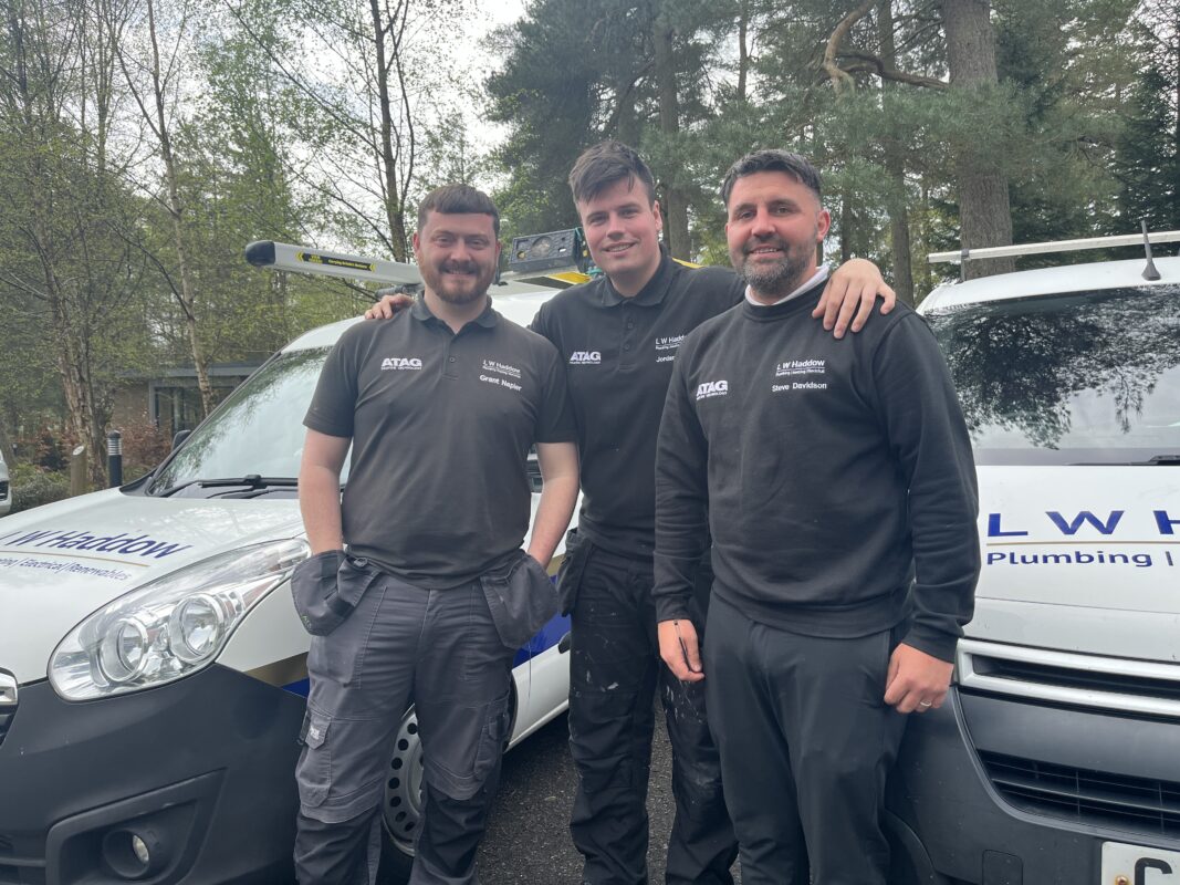 A team of plumbing, heating and electrical engineers standing infrot of their vans.