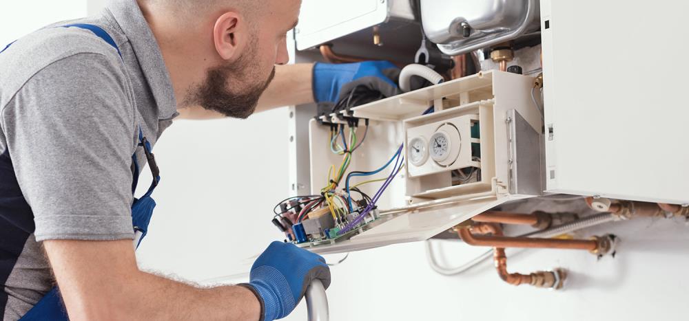 A technician is checking the boiler to ensure there is no leak